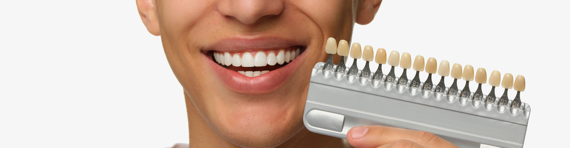 Man holding tooth shade-matching tool next to his smile.